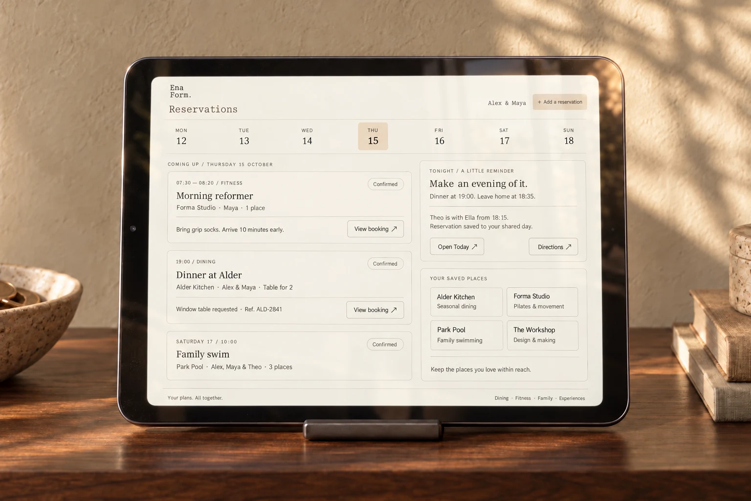 Close-up of an iPad mini on the walnut console, showing dining, fitness and family reservations.